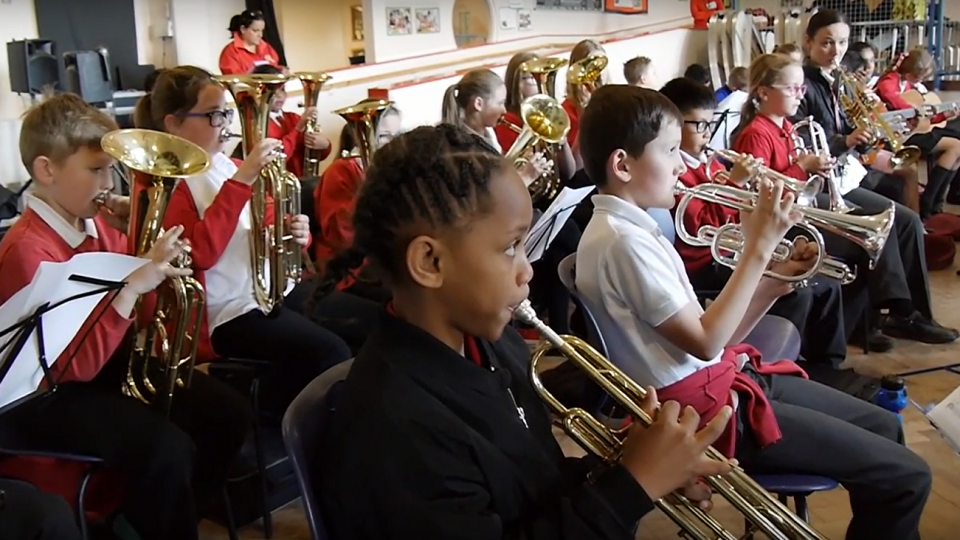 A group of children with mixed identities all playing brass instruments