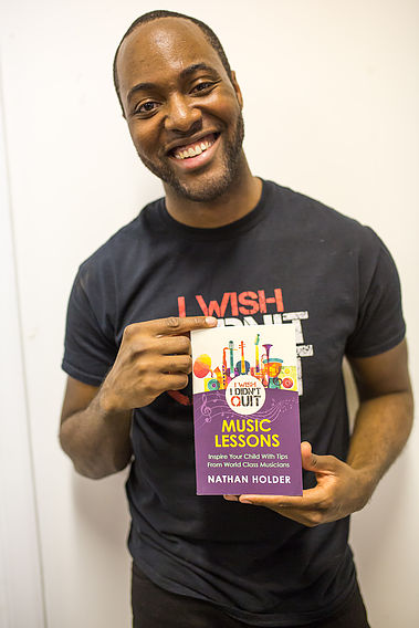 A black, masculine adult holding a flyer promoting having music lessons as a child.
