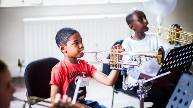 two young boys playing one-handed trumpets