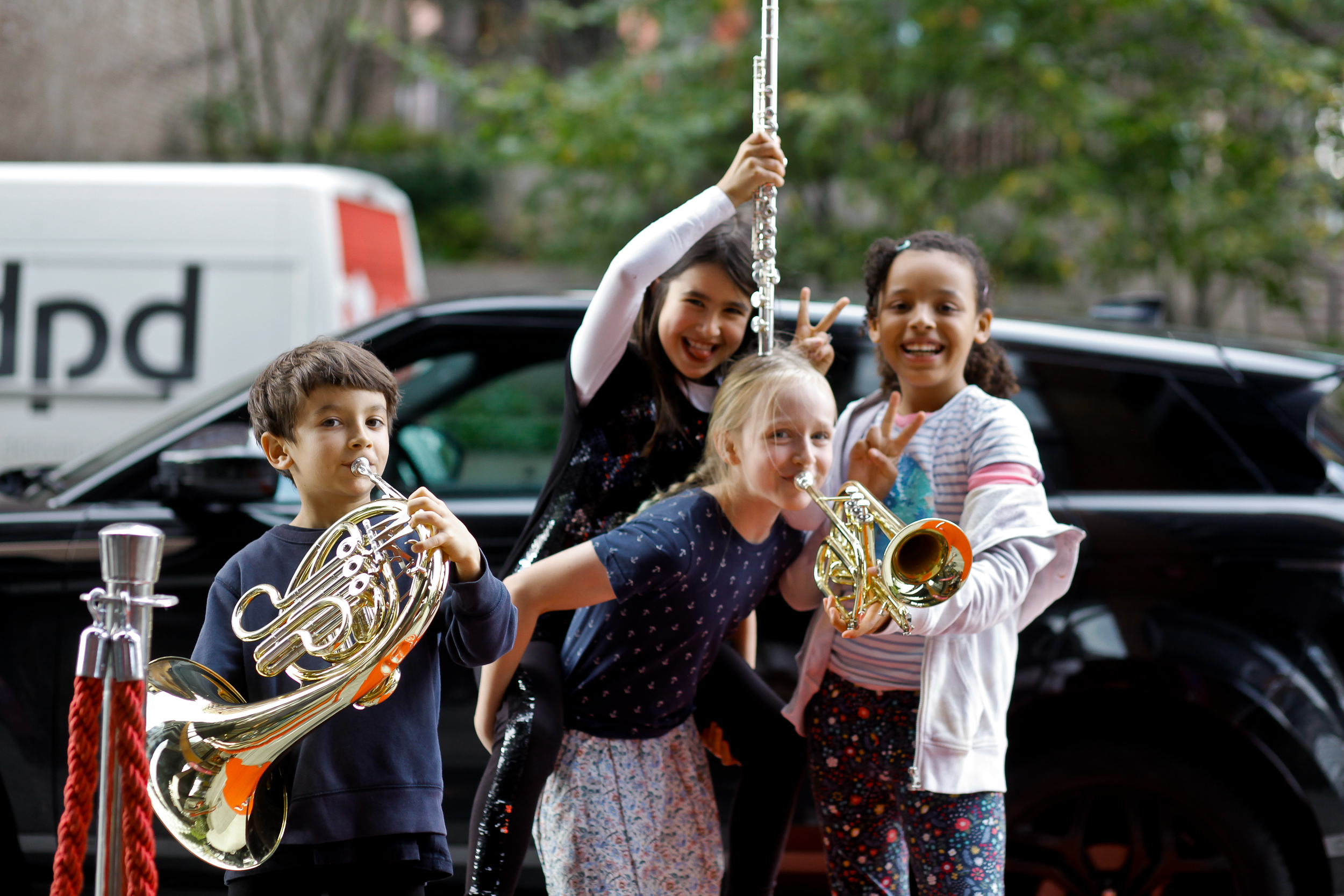 four young people pose playfully with different instruments